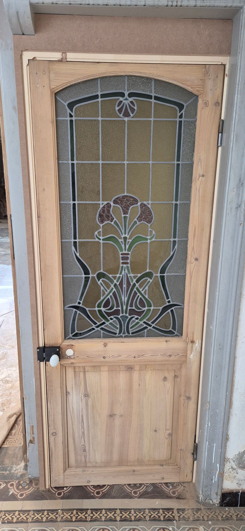 Porte en bois avec panneau en vitrail à motif floral.
