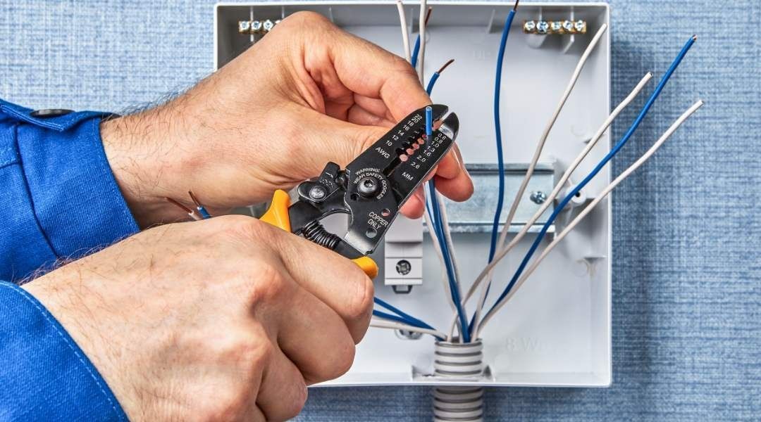 Un hombre está cortando cables con un pelacables.