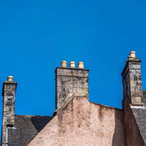Un edificio con tres chimeneas en la parte superior contra un cielo azul.