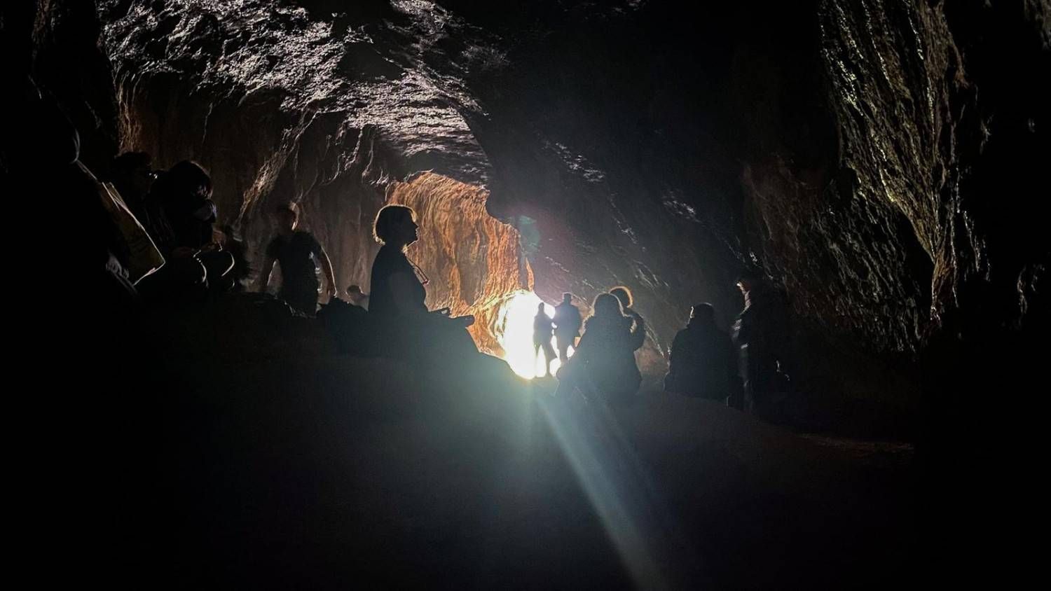 Personas recortadas contra el cielo en un túnel oscuro observando un brillante espectáculo de fuegos artificiales.