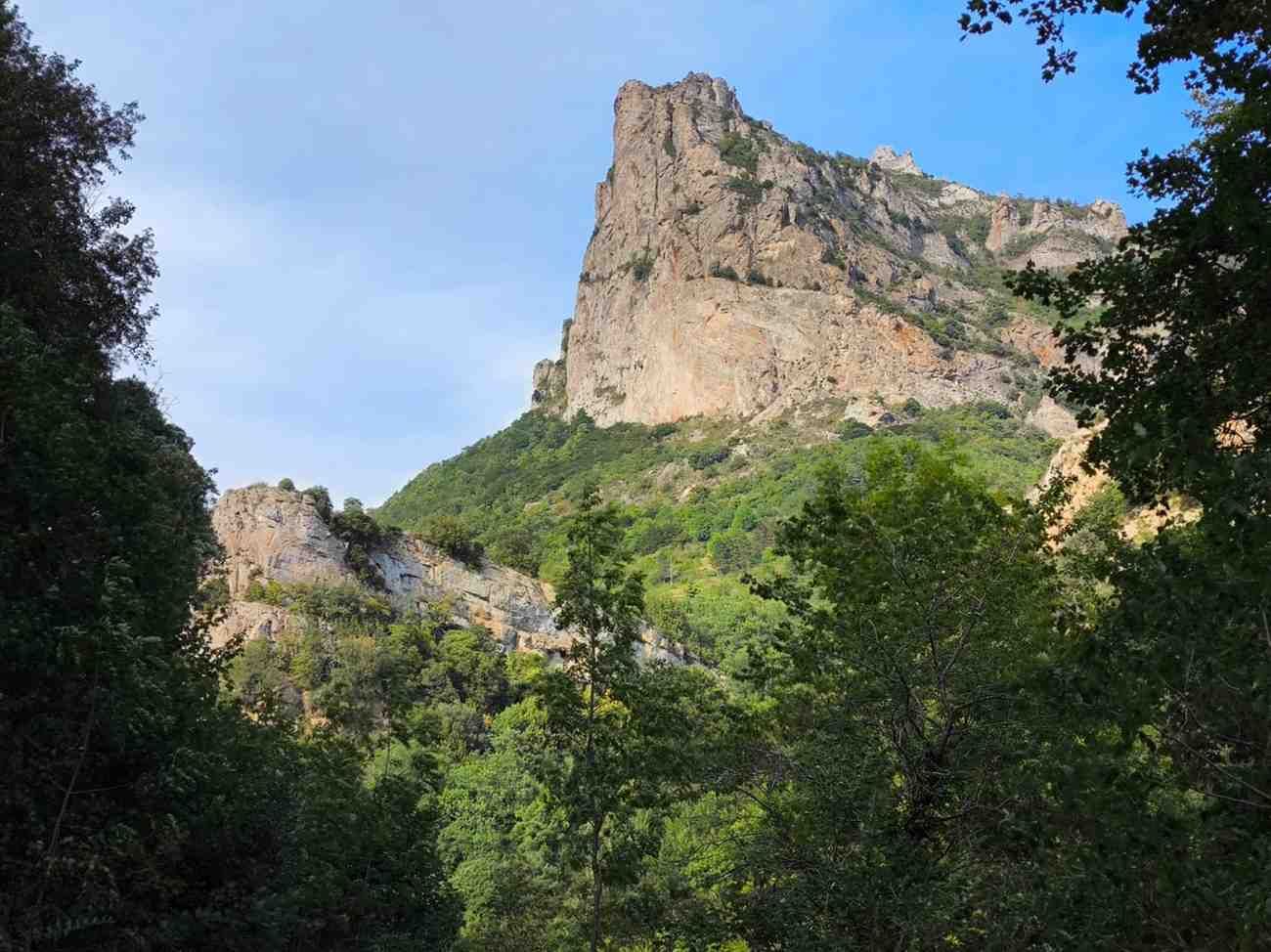 Escarpado acantilado rocoso sobre árboles verdes bajo un cielo azul