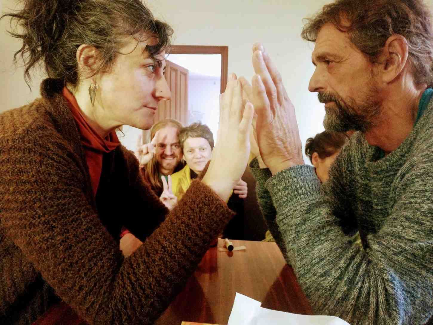 Dos personas se miran una a la otra con las manos levantadas, tocándose las palmas en un ambiente interior acogedor.