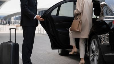 Offener SUV-Kofferraum mit zwei bunten Koffern bei der Abgabe am Flughafen-Bordstein