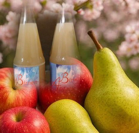 Birnen und Äpfel neben zwei Flaschen Getränken vor einem zarten floralen Hintergrund