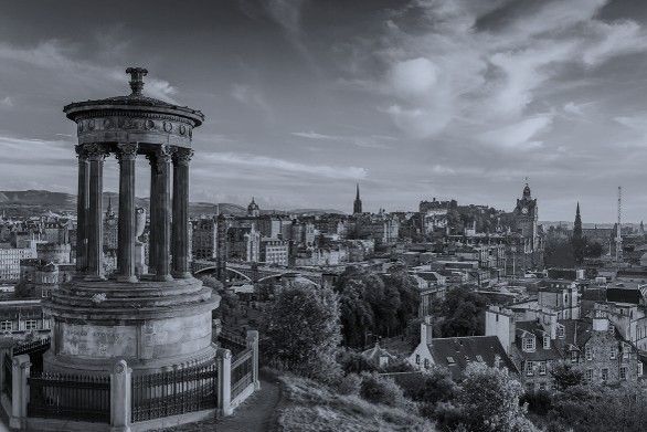 Panoramaansicht der Stadtsilhouette mit einem Steinmonument im Vordergrund unter einem bewölkten Himmel