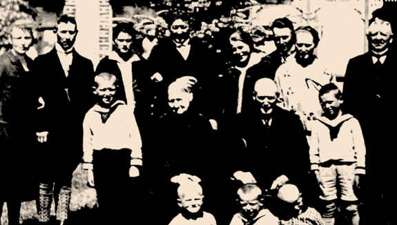 Eine Gruppe von Menschen posiert im Freien auf einem alten Schwarz-Weiß-Foto.