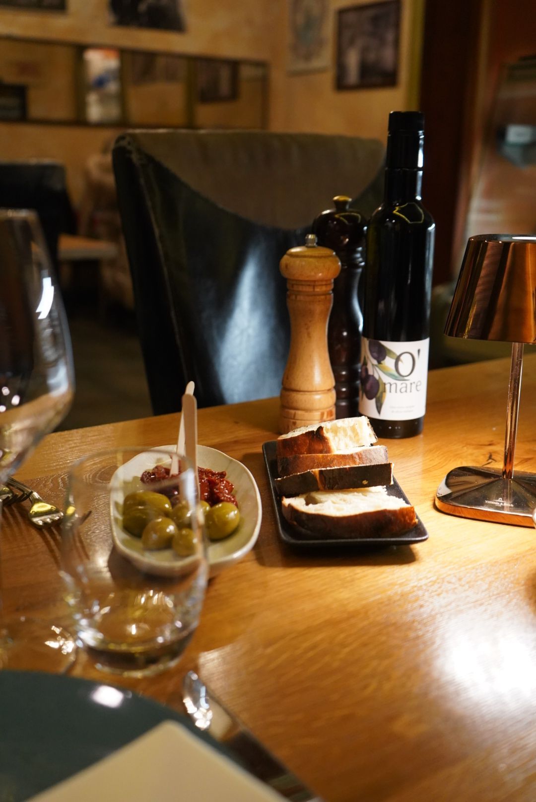 Tischdekoration mit Oliven, Brot, Öl und Kerze in einem Restaurant.