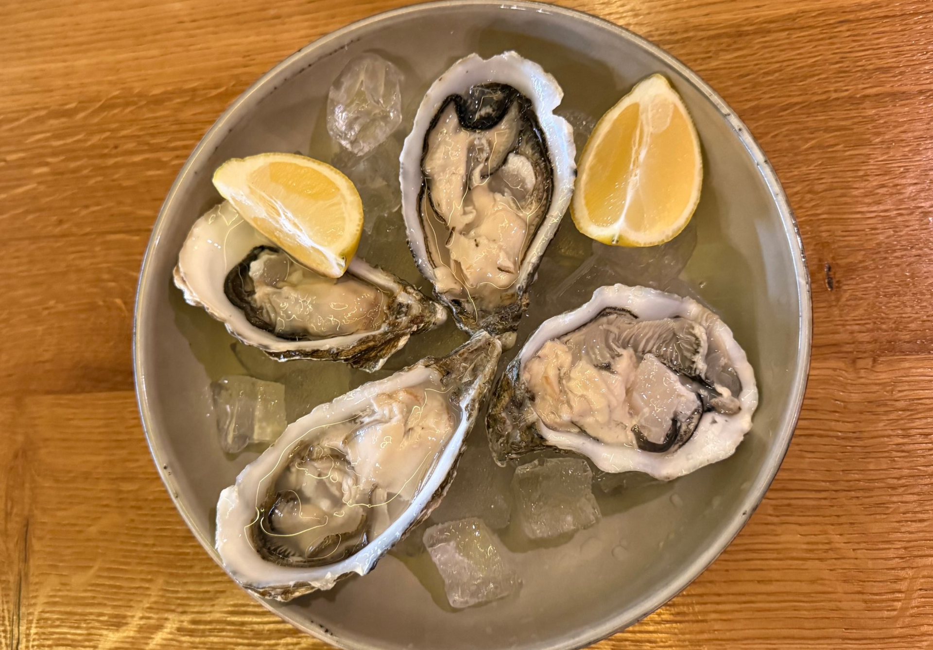 Teller mit Austern auf Eis und Zitronenspalten.