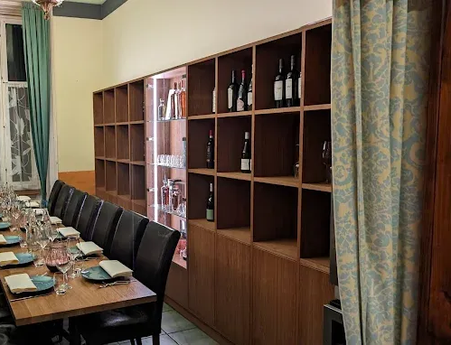 Lange Holzregale mit Weinflaschen und Gläsern in einem Esszimmer mit einem langen, zum Essen gedeckten Tisch.