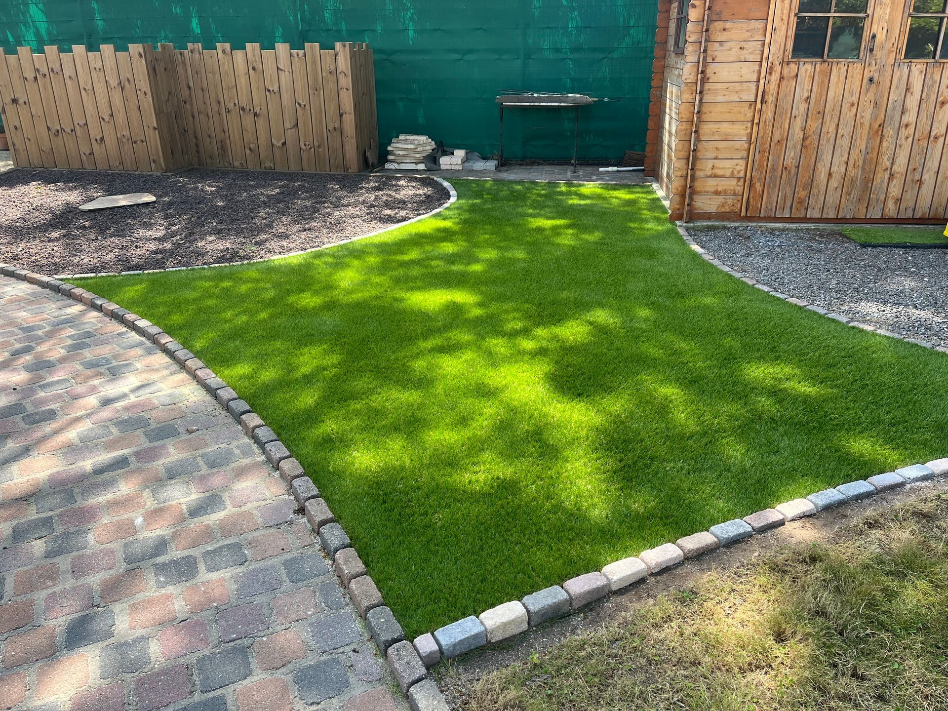 Réalisation d'un parterre en herbe en forme de losange avec des pavés pour délimiter les contours