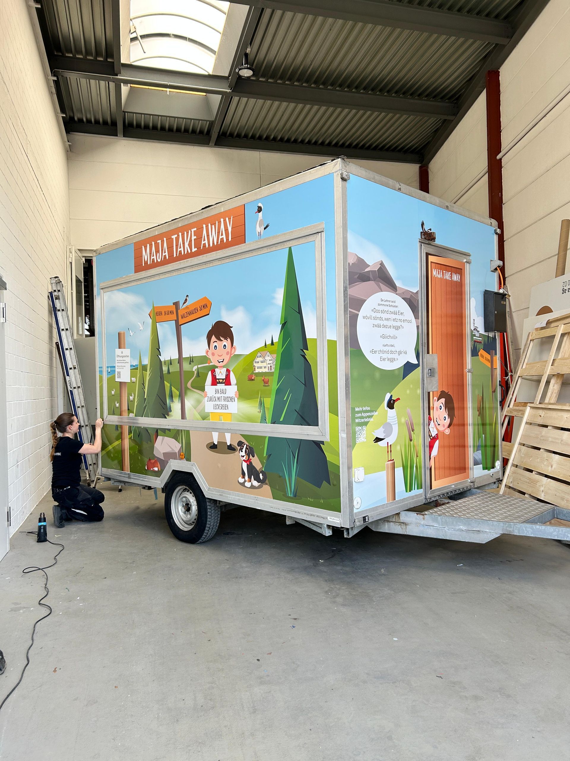 Chefs in white coats and black gloves packing food in a brown paper bag in a commercial kitchen.