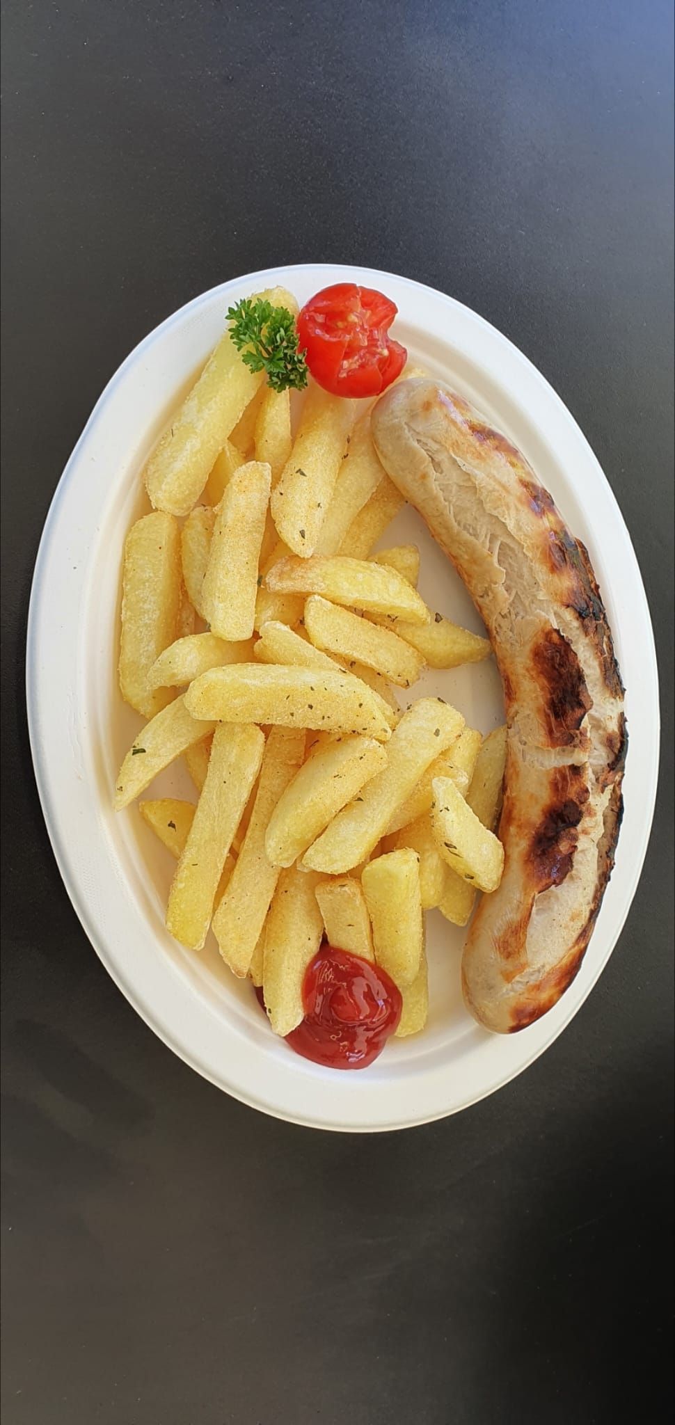 Person using a knife and fork to cut dessert on a white plate; a bowl of bread, flowers.