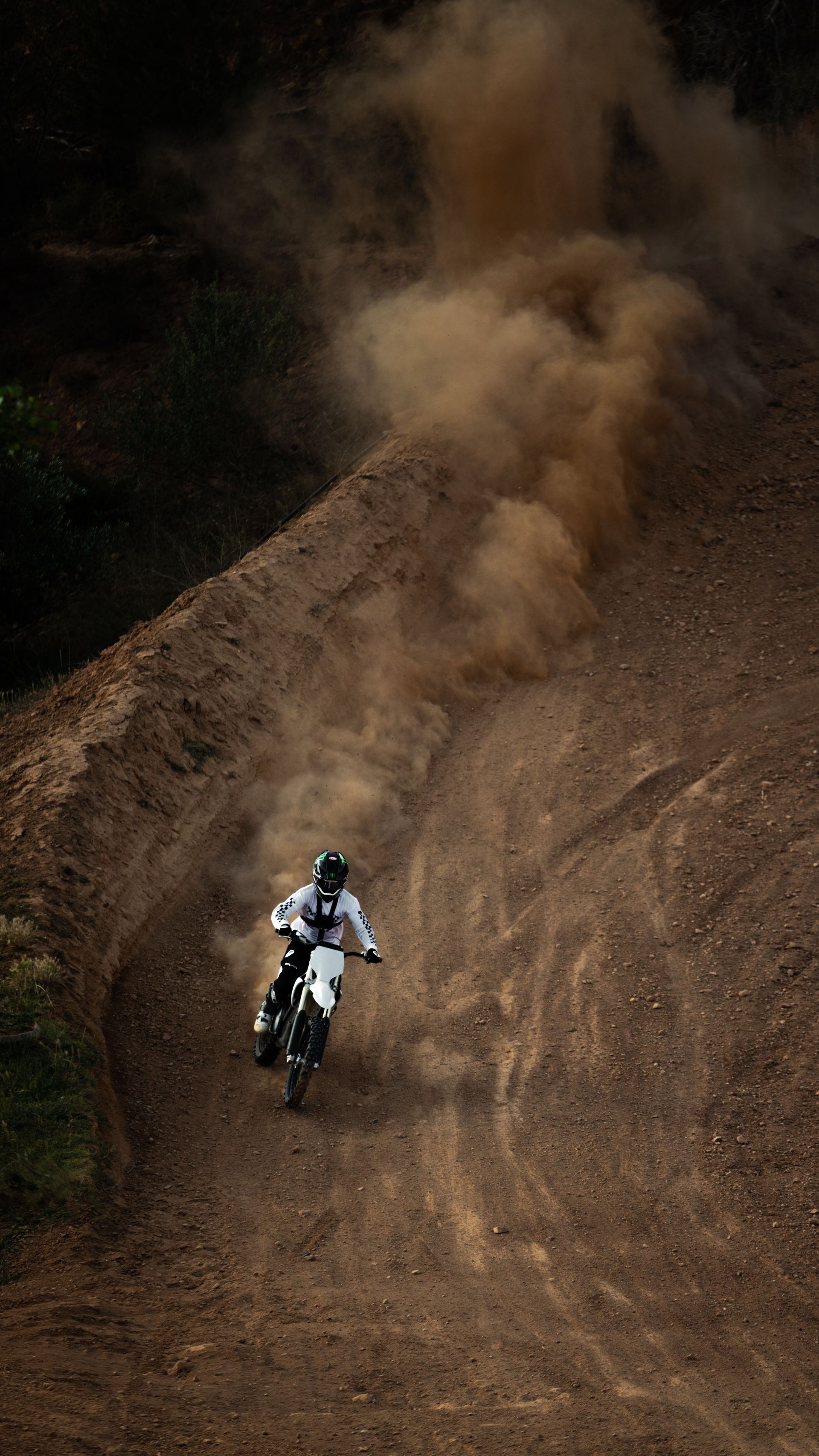 Ein Mann fährt mit einem Dirtbike einen Feldweg entlang.