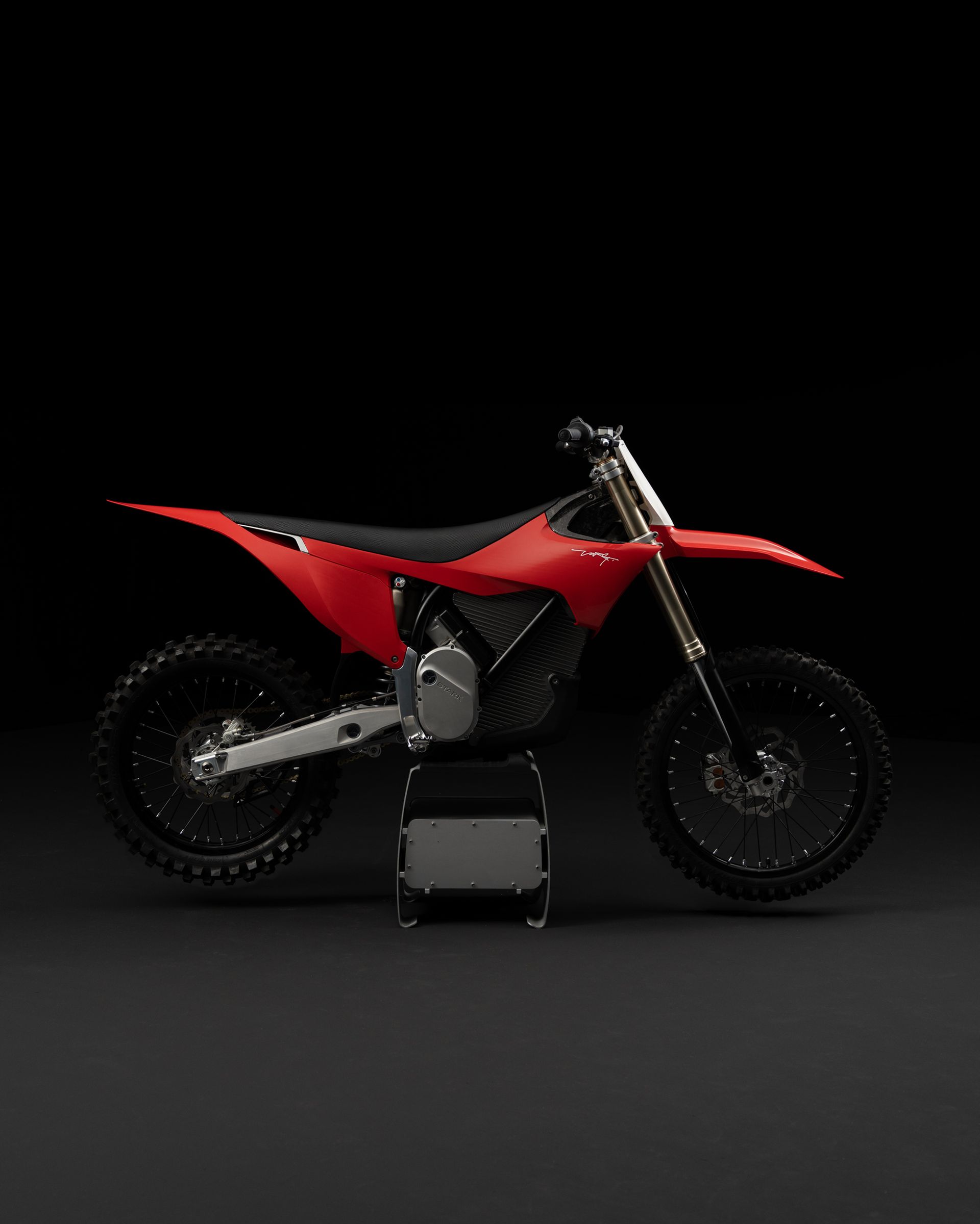 Ein rotes Dirtbike ist auf einer schwarzen Fläche geparkt.