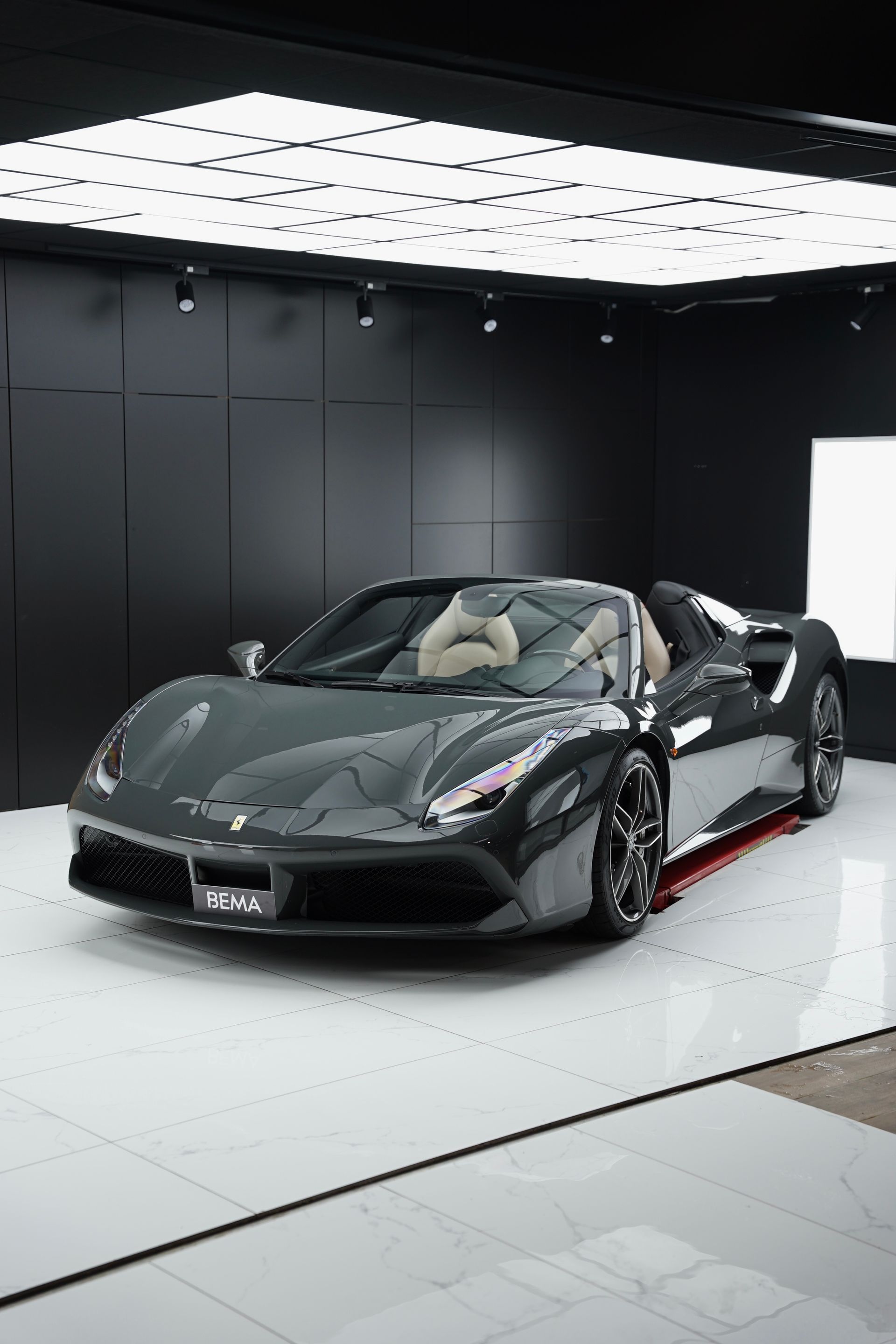 Ferrari décapotable grise dans un showroom moderne et sombre.