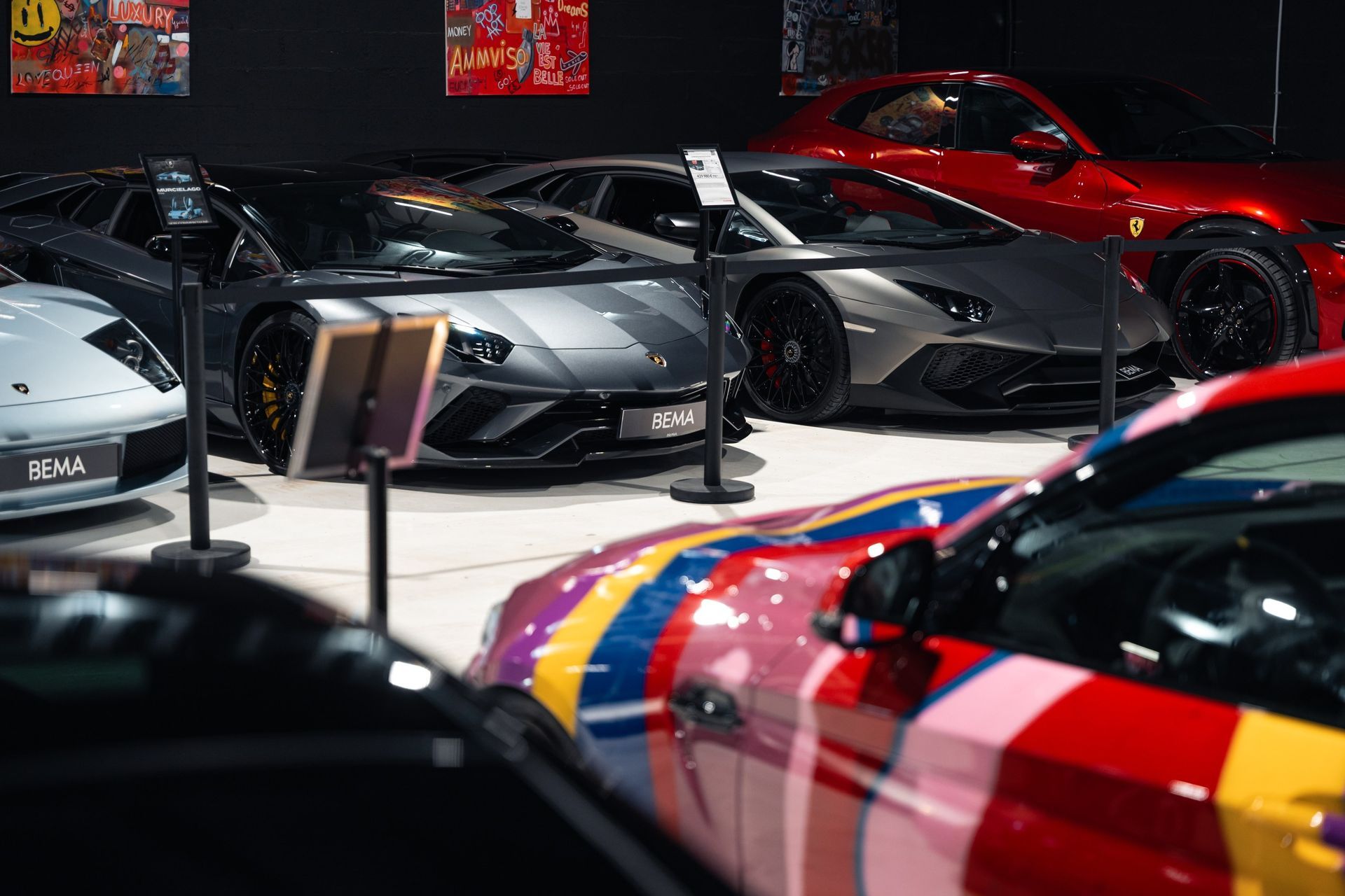 Salle d'exposition de voitures de luxe avec diverses voitures de sport, dont une à motifs colorés.