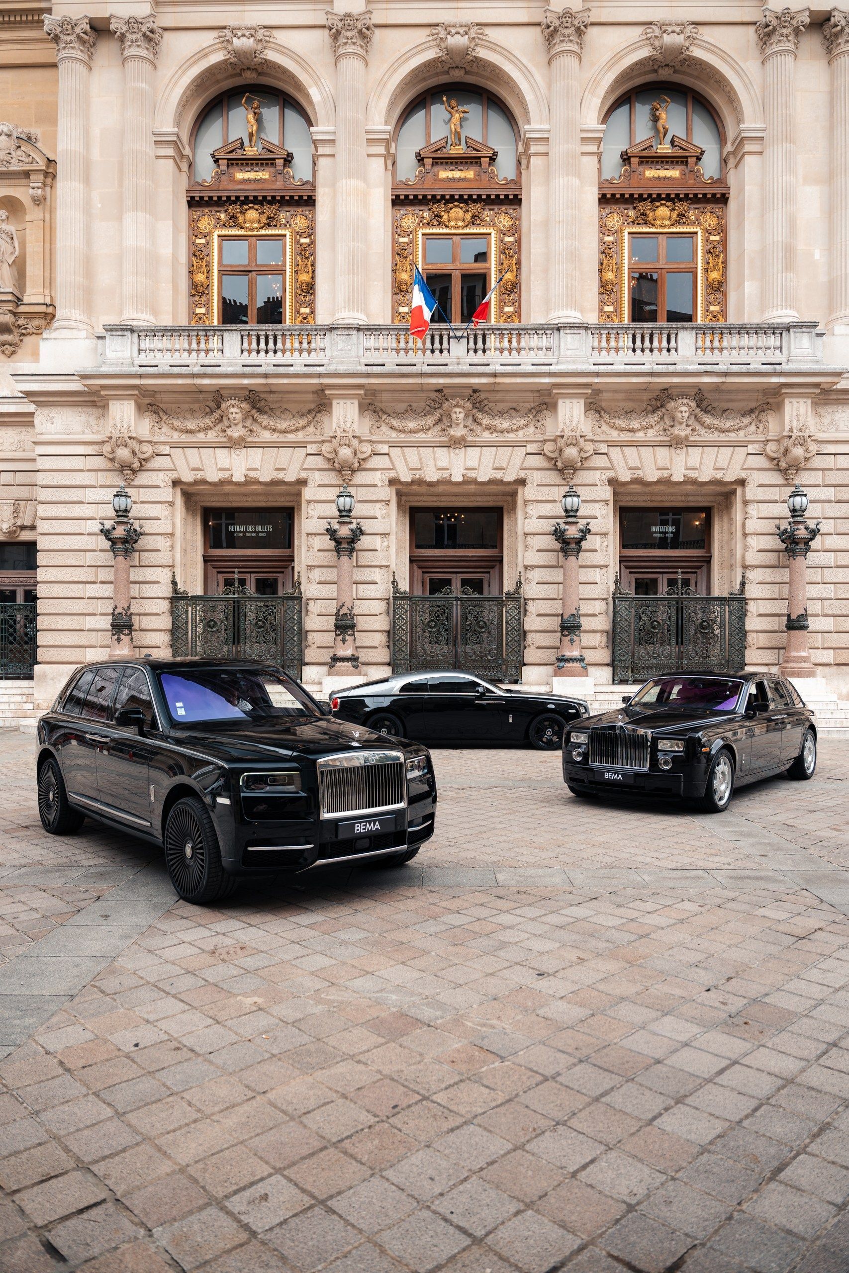 Trois voitures Rolls-Royce noires garées devant un bâtiment décoré de couleur claire avec des drapeaux français.