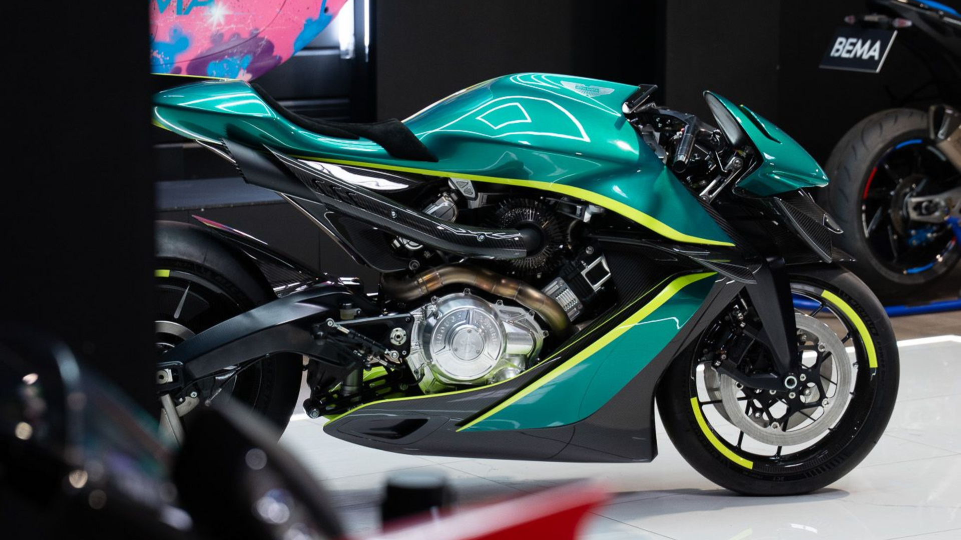 Une moto BMW S 1000 R noire, bleue et orange avec le logo M est garée à l'extérieur.