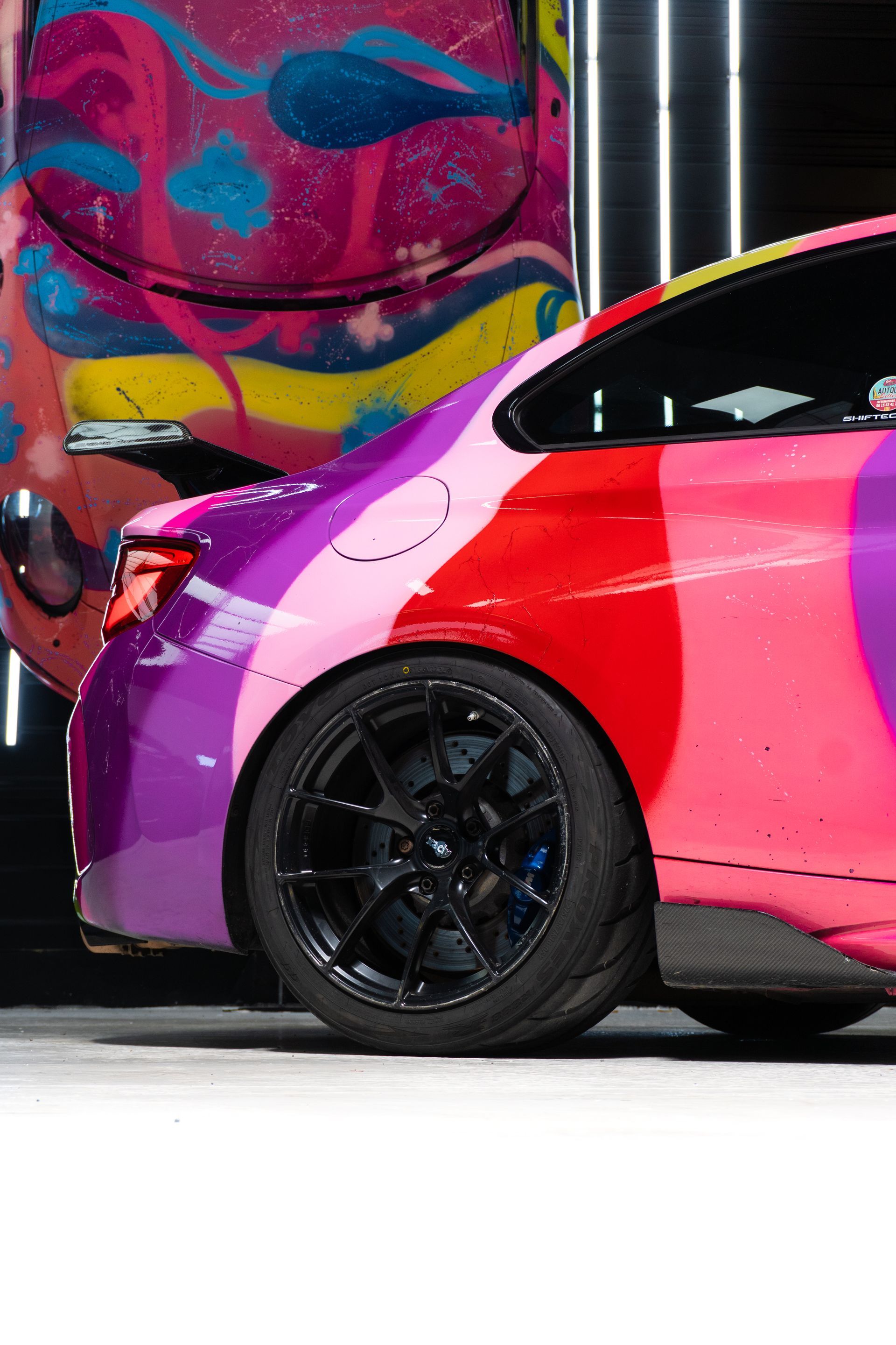 Voiture de sport colorée avec un design de peinture unique et des roues noires.