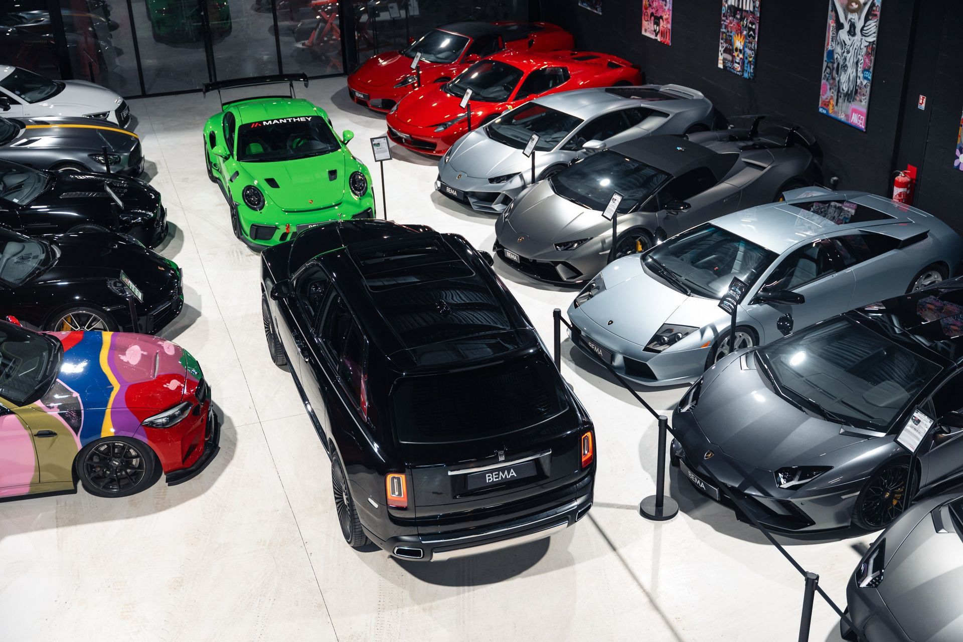 Salle d'exposition de voitures de luxe avec différentes voitures de sport de couleurs exposées.