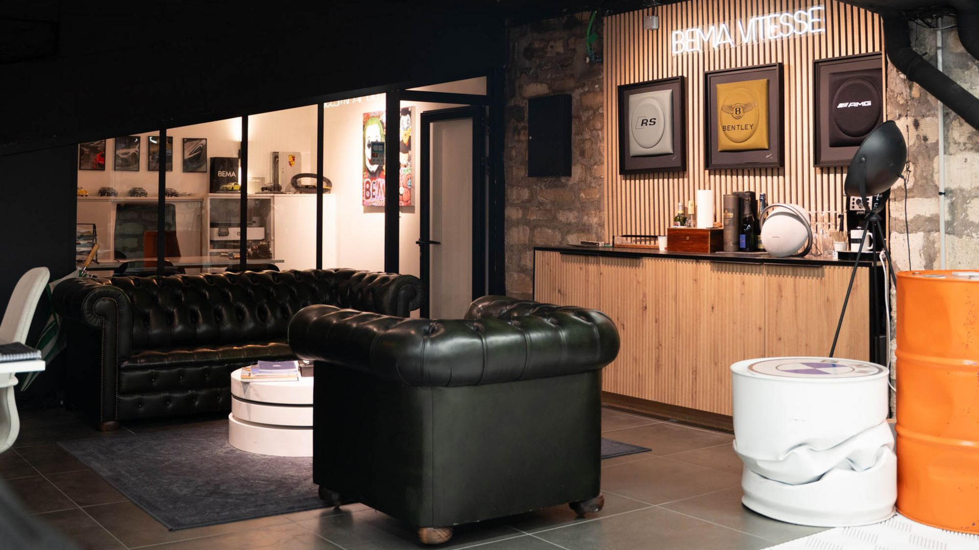 Intérieur élégant et sombre avec fauteuil en cuir et espace d'attente. Trois prix encadrés sont accrochés à un mur en bois.