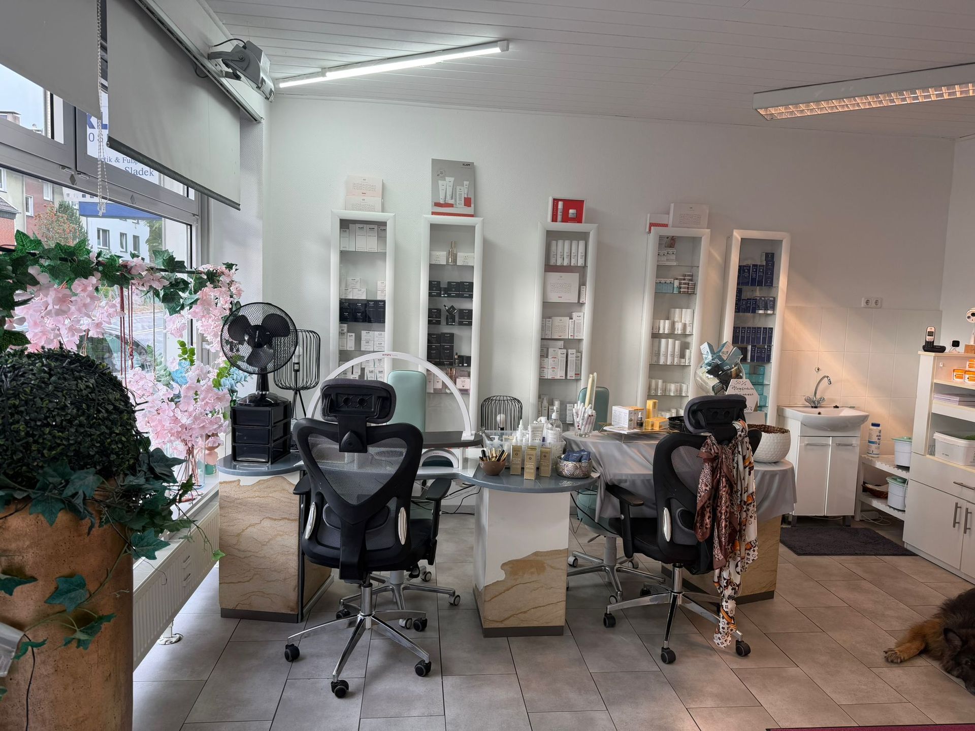 Heller Behandlungsraum eines Kosmetik- und Fußpflegeinstituts mit Behandlungsliegen und Produktregalen