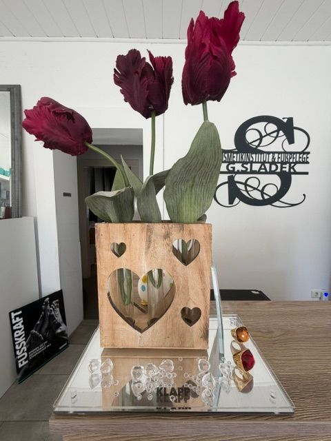 Dekorative Blumen vor dem Logo des Kosmetik- und Fußpflegeinstituts