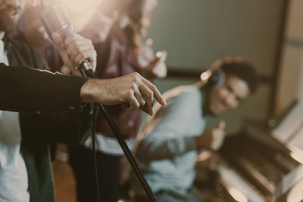 Un grupo de personas está cantando frente a micrófonos en un estudio de grabación.