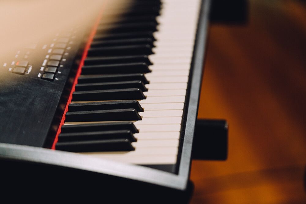 Un primer plano de un teclado de piano sobre un piso de madera.