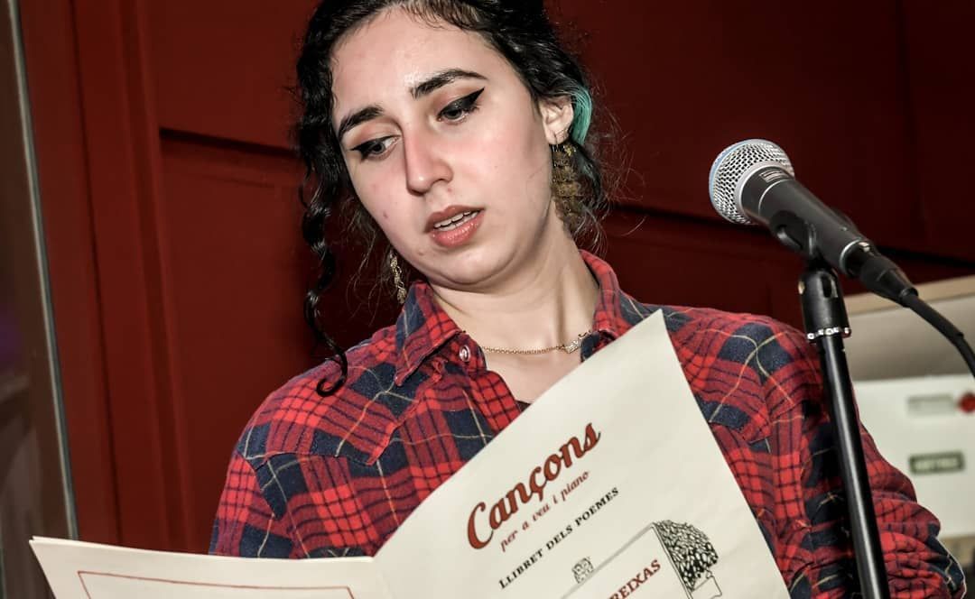 Una mujer está leyendo un menú frente a un micrófono.