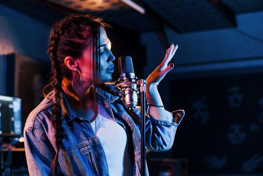 Una mujer está cantando frente a un micrófono en un estudio de grabación.
