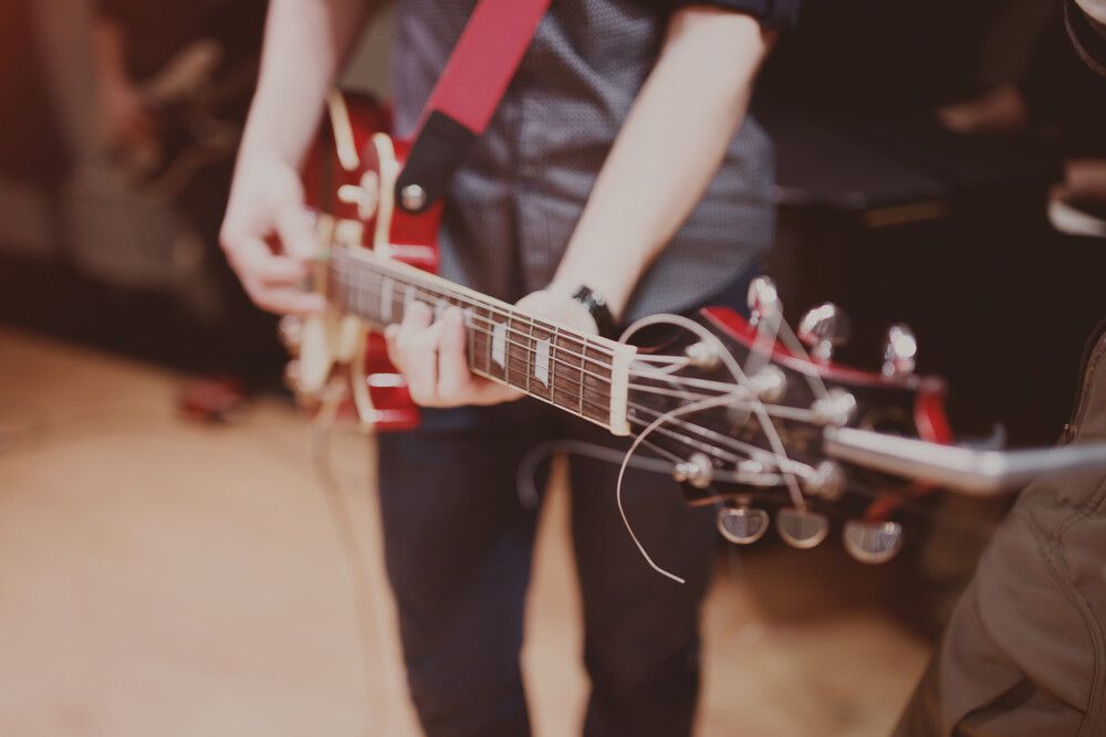 Una persona está tocando una guitarra con una correa roja.