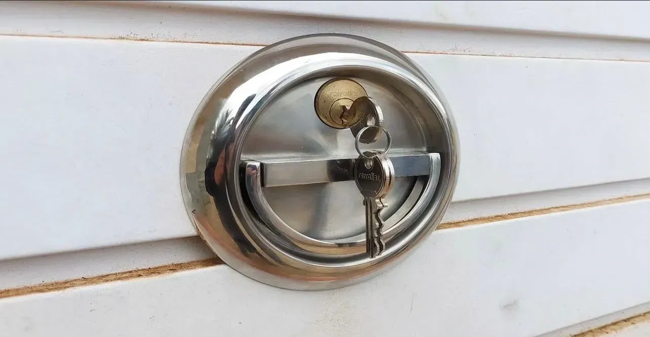 Cornamusa cromada montada sobre revestimiento de madera pintado de blanco.