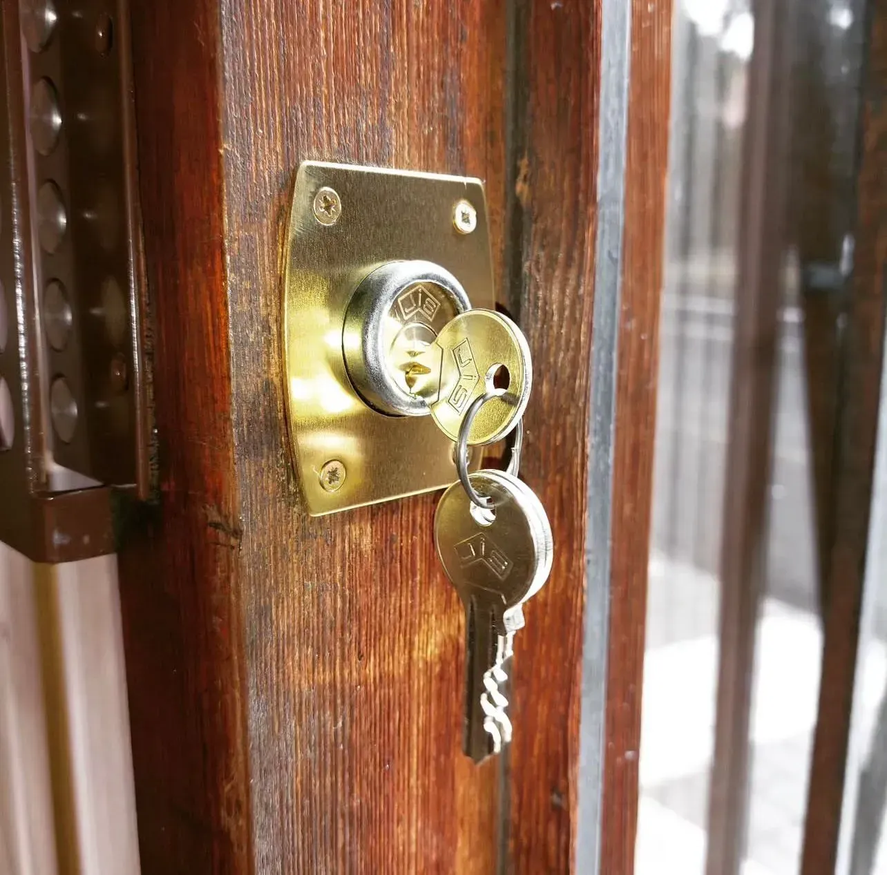 Primer plano de una cerradura de latón con una llave insertada en una puerta de madera.