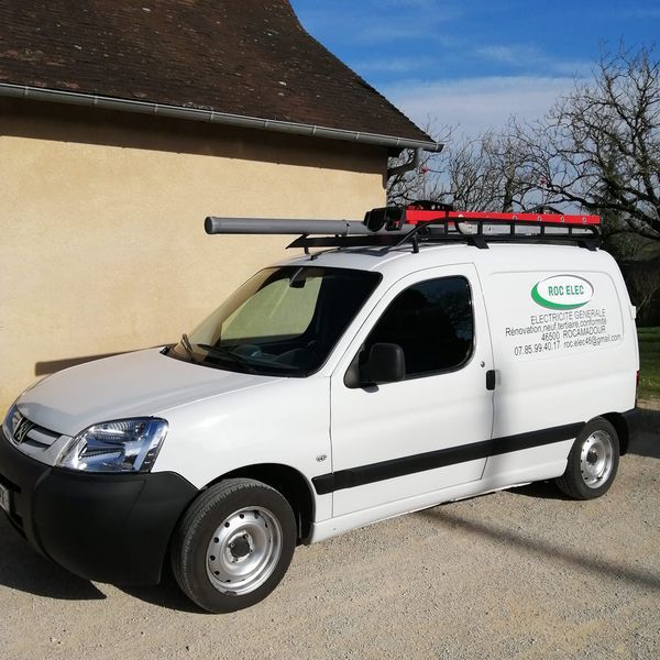 Un utilitaire blanc avec des matériaux sur le toit.