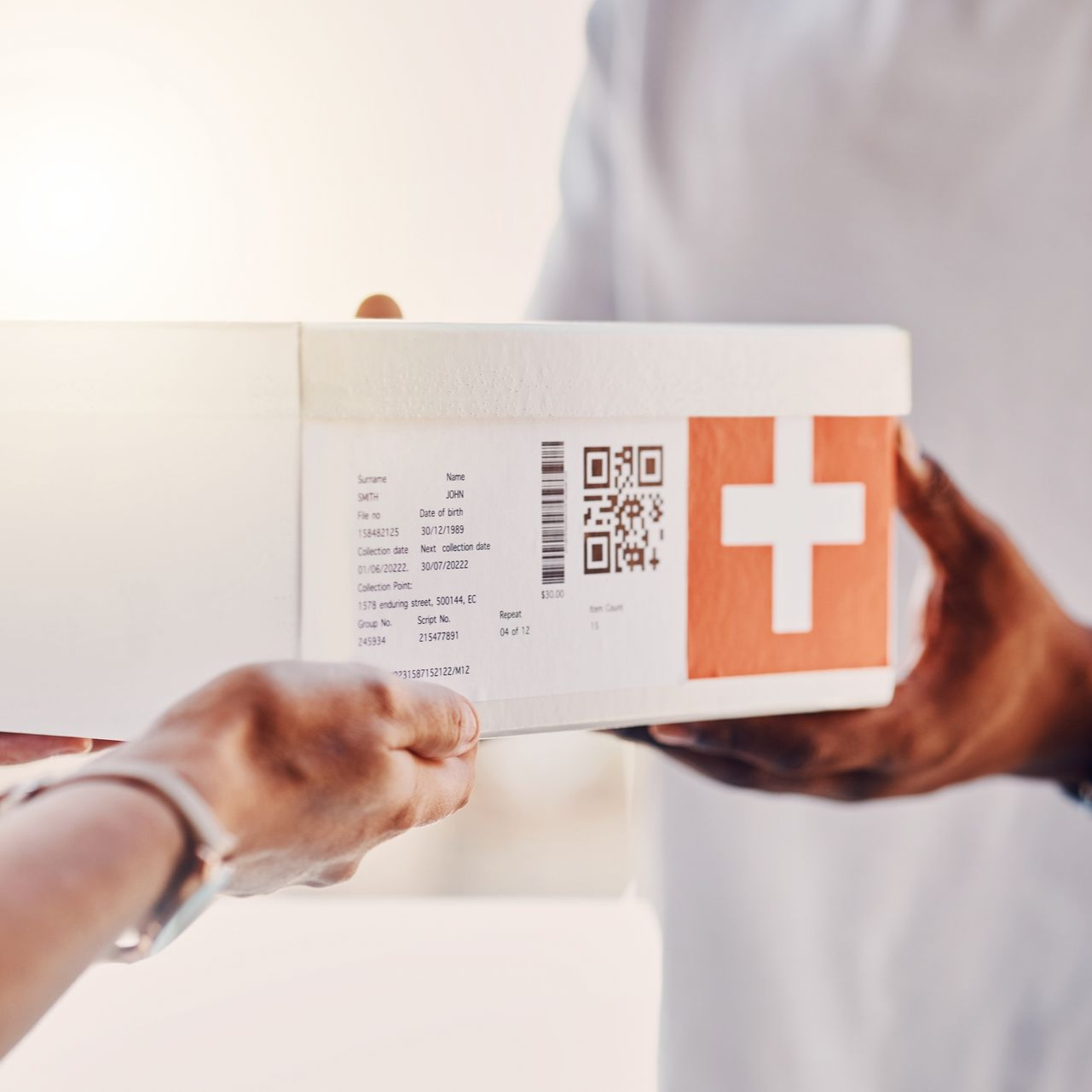 Des mains échangent une boîte blanche avec une croix médicale, probablement une livraison médicale.