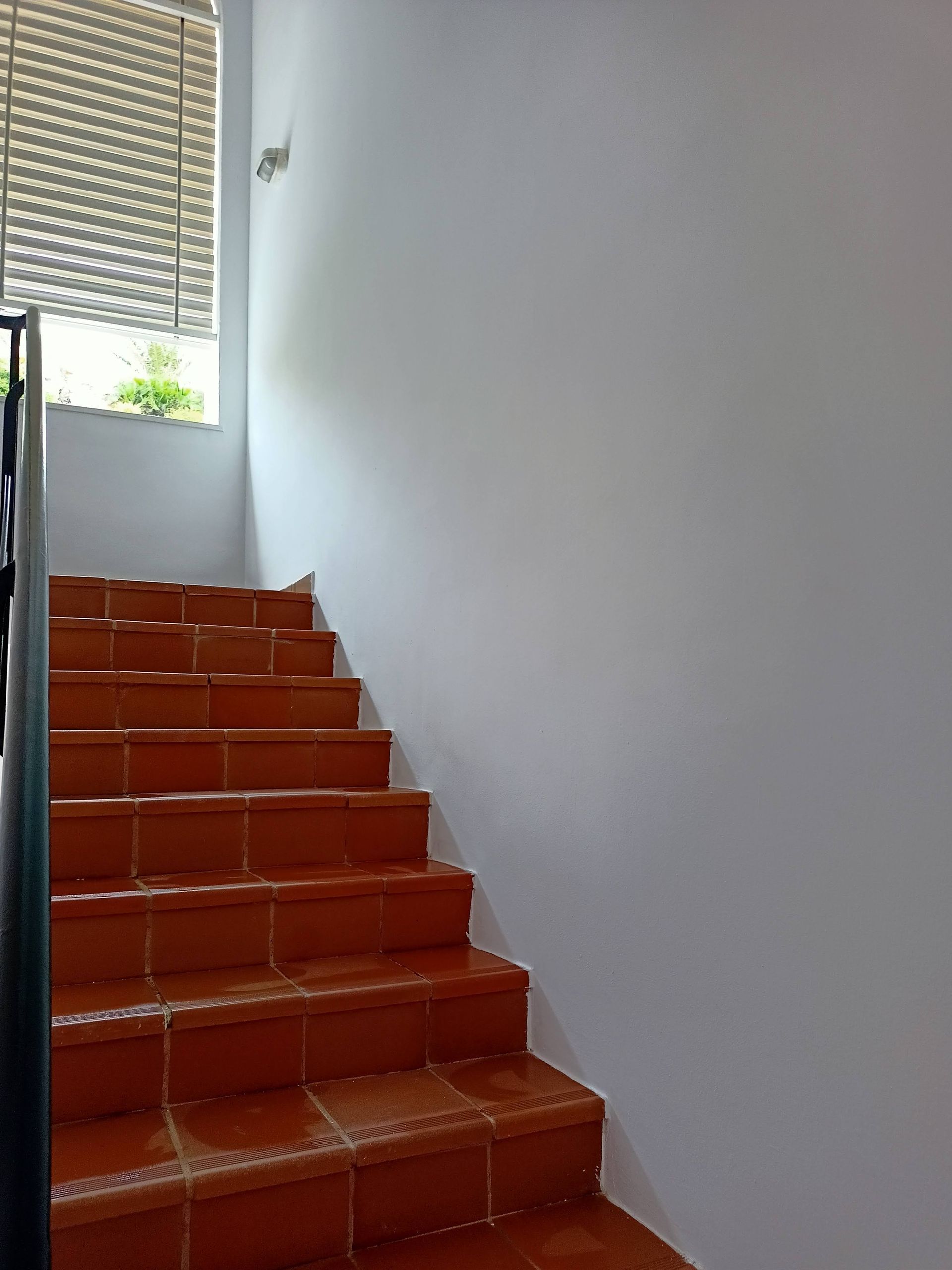 Un conjunto de escaleras de baldosas rojas que conducen a una pared blanca.