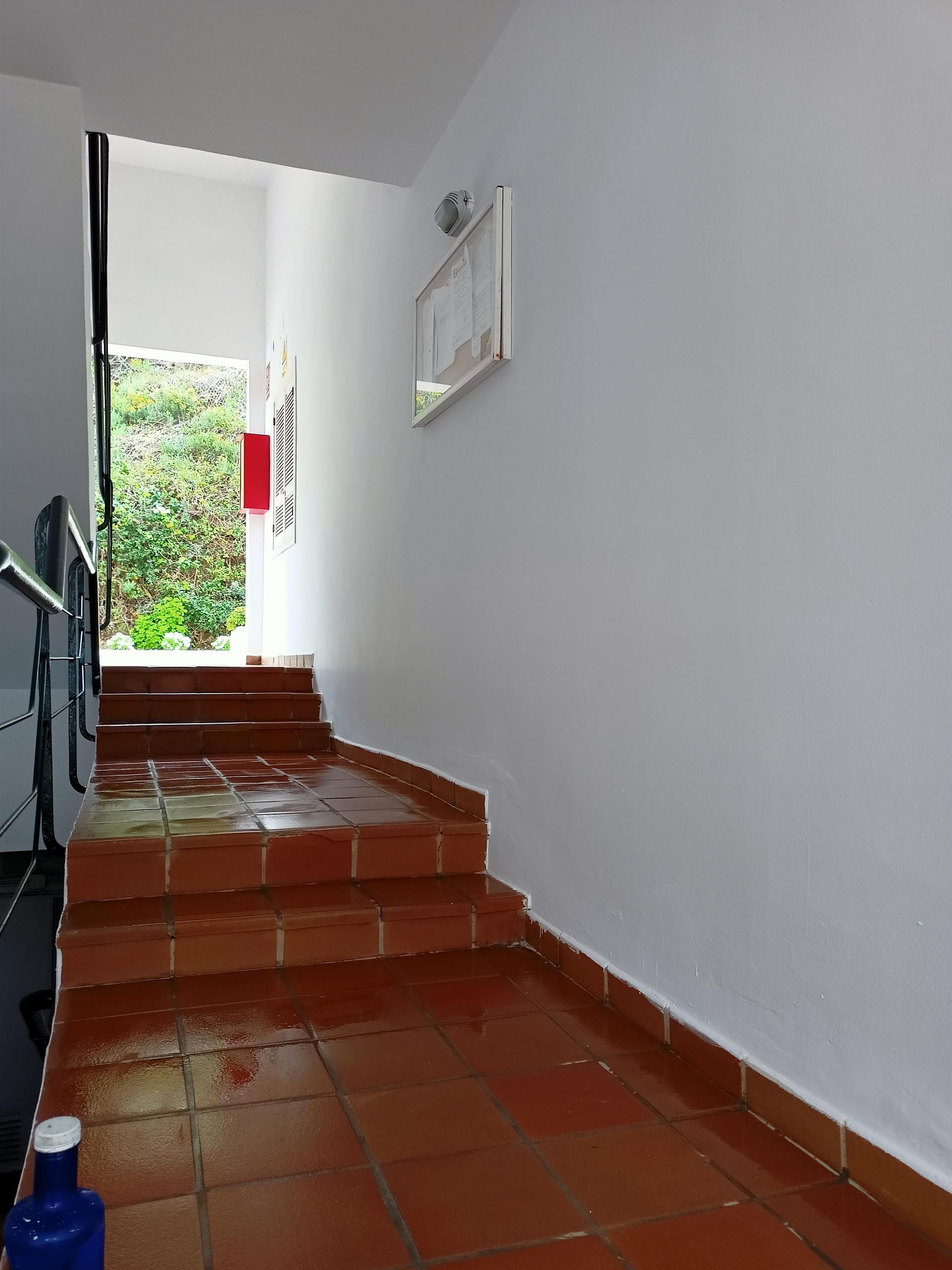 Un pasillo con escaleras y una pared blanca.