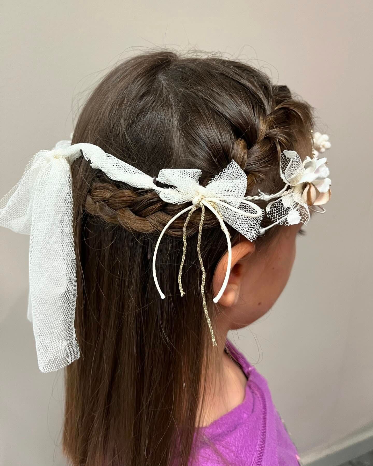 Chica de cabello castaño con diadema floral y peinado trenzado.