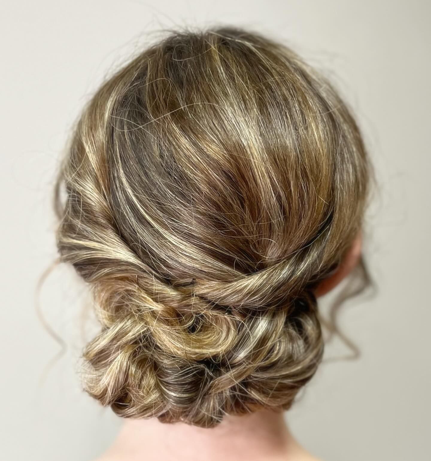 Cabello de mujer peinado en un recogido, un moño bajo con giros y reflejos.