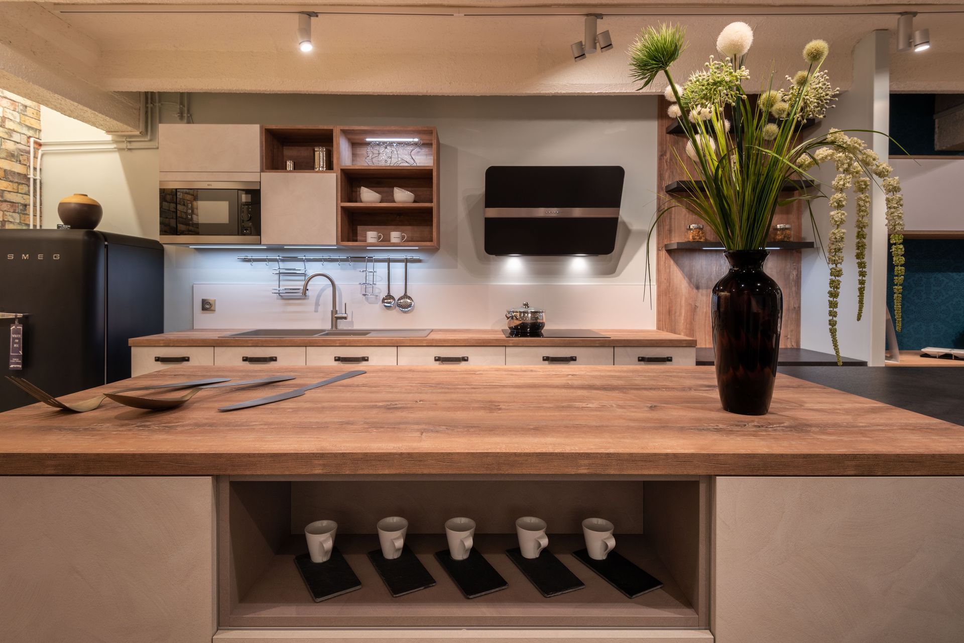 Cuisine moderne avec un îlot en bois, des armoires blanches et un vase de fleurs au premier plan.