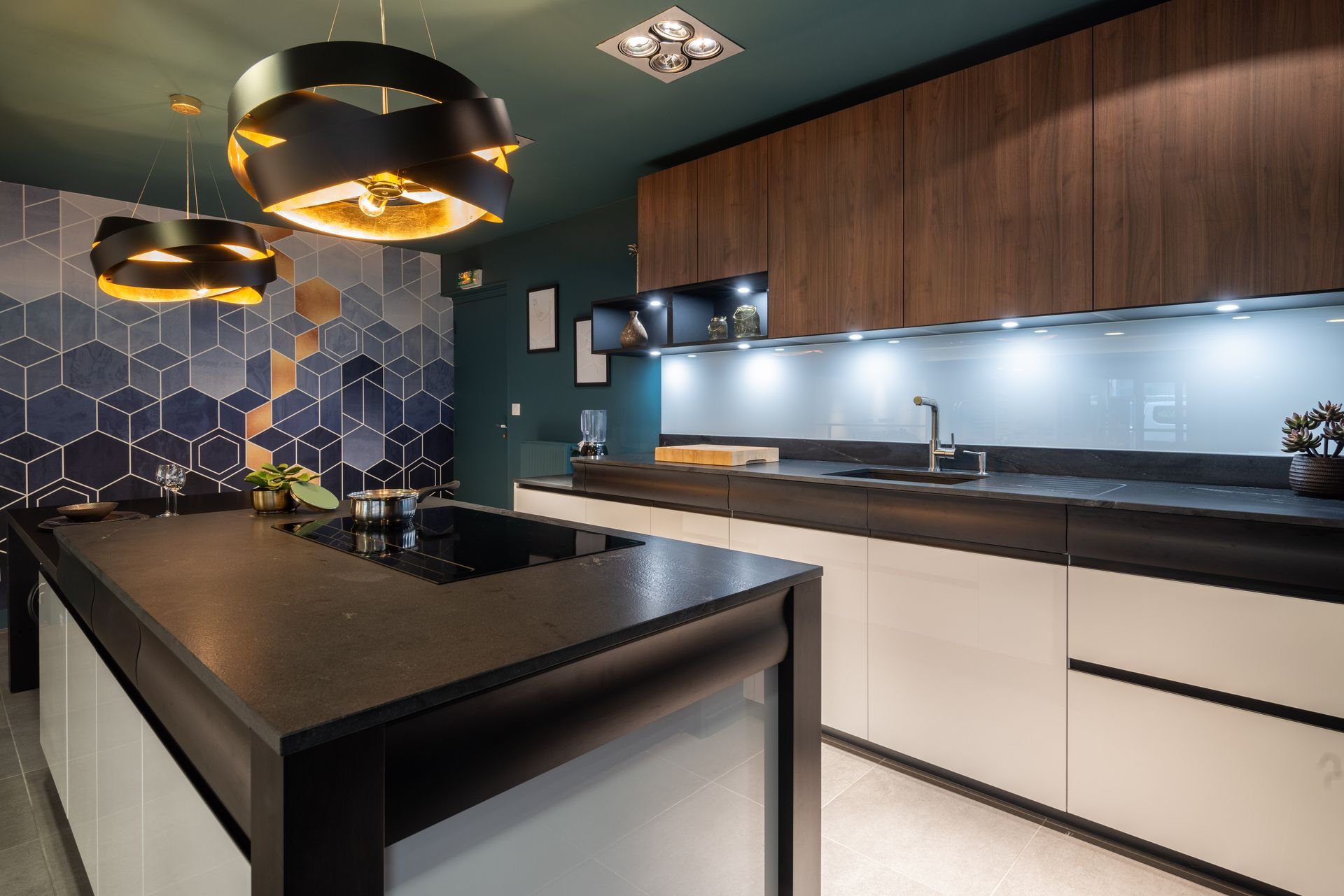 Cuisine moderne avec îlot noir, armoires blanches et luminaires suspendus.