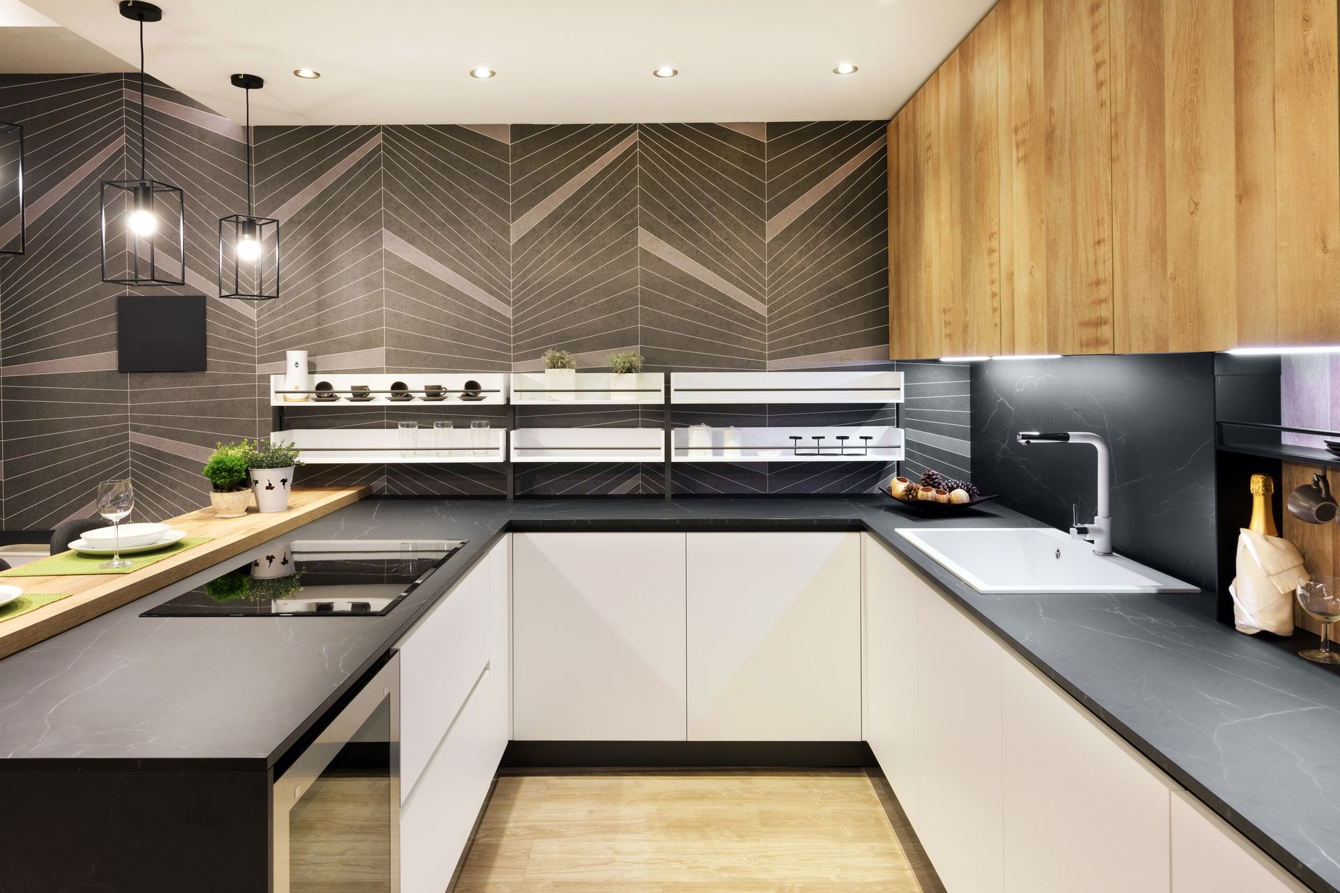 Cuisine moderne avec comptoirs noirs, placards blancs et crédence en carrelage à chevrons.