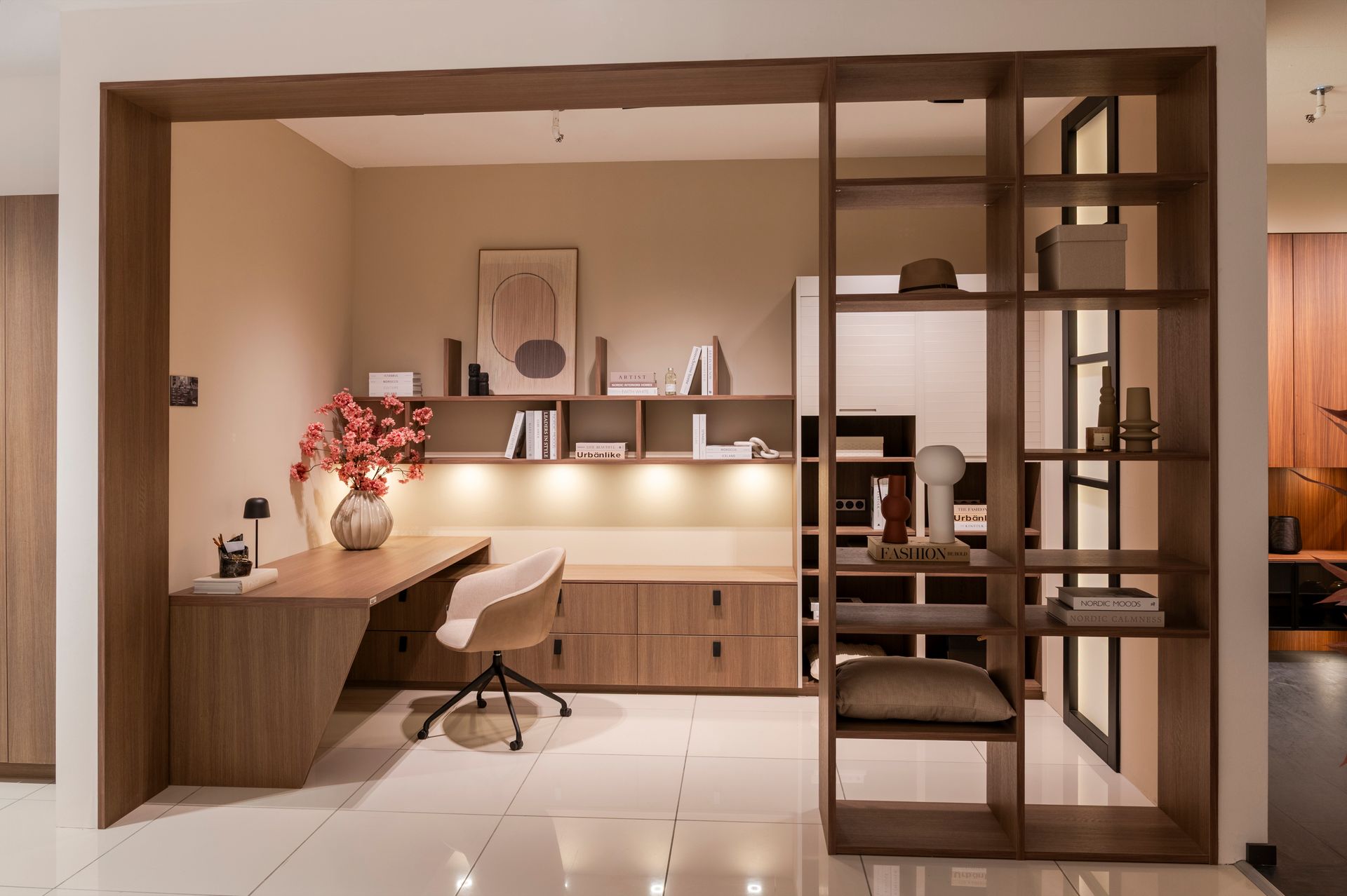 Espace de travail moderne et minimaliste avec bureau en bois, chaise, étagères et éclairage chaleureux.
