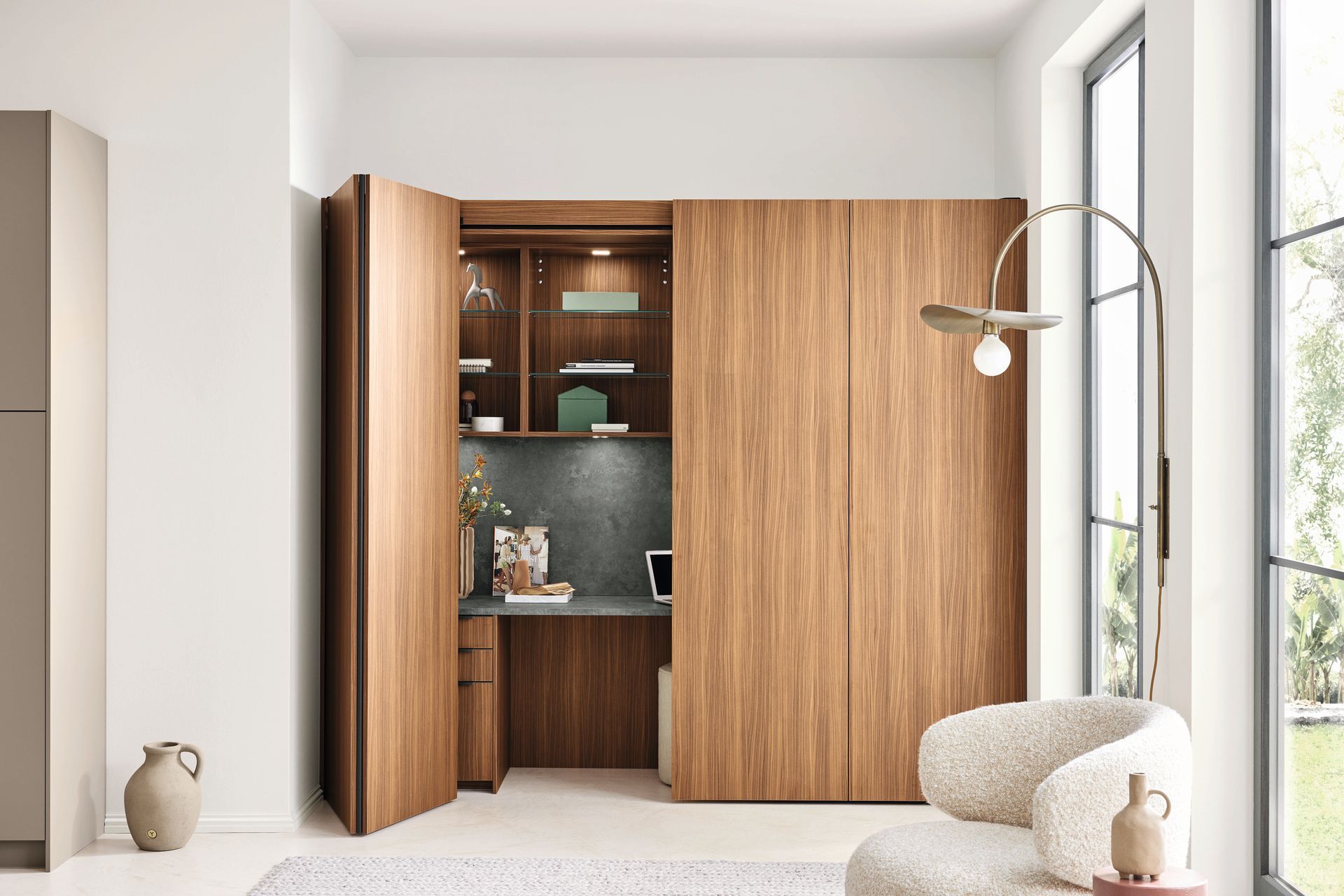 Salon moderne avec armoire en bois, étagères ouvertes et fenêtres allant du sol au plafond.