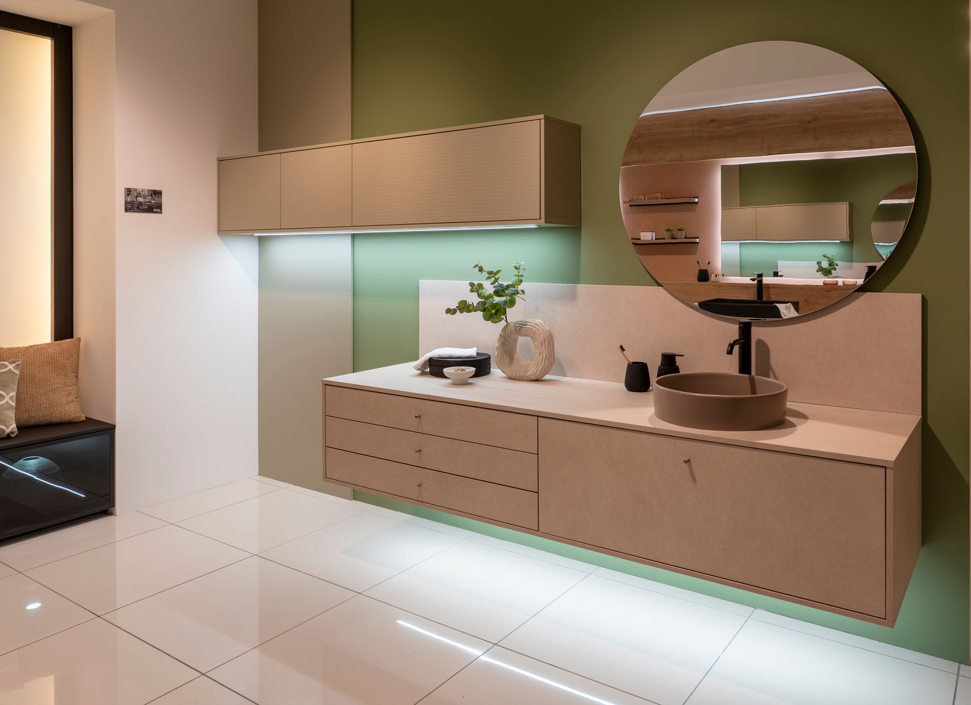 Meuble lavabo moderne avec miroir rond, comptoir blanc et mur d'accent vert.