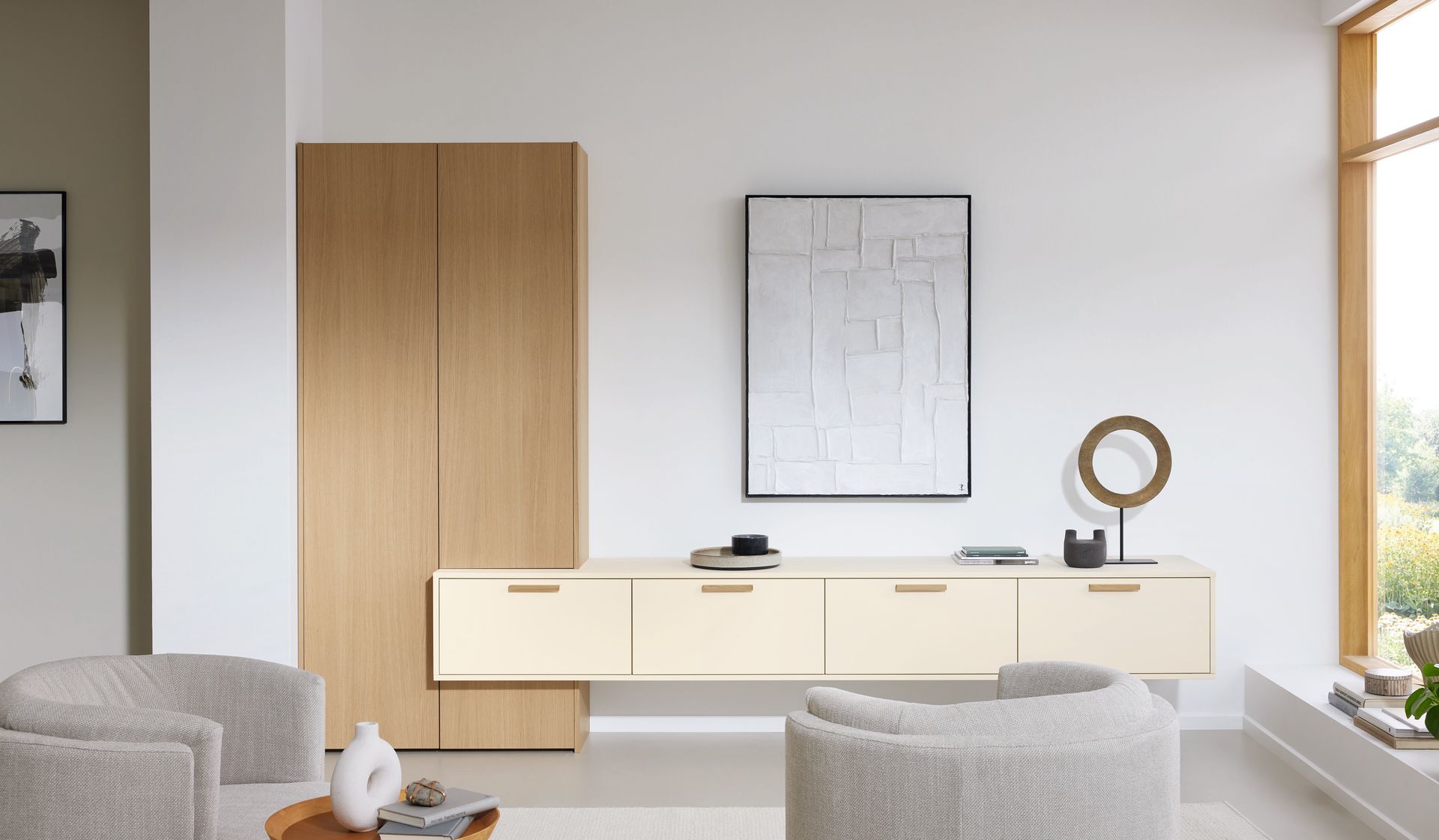Salon minimaliste avec buffet crème, fauteuils gris et armoire en bois.