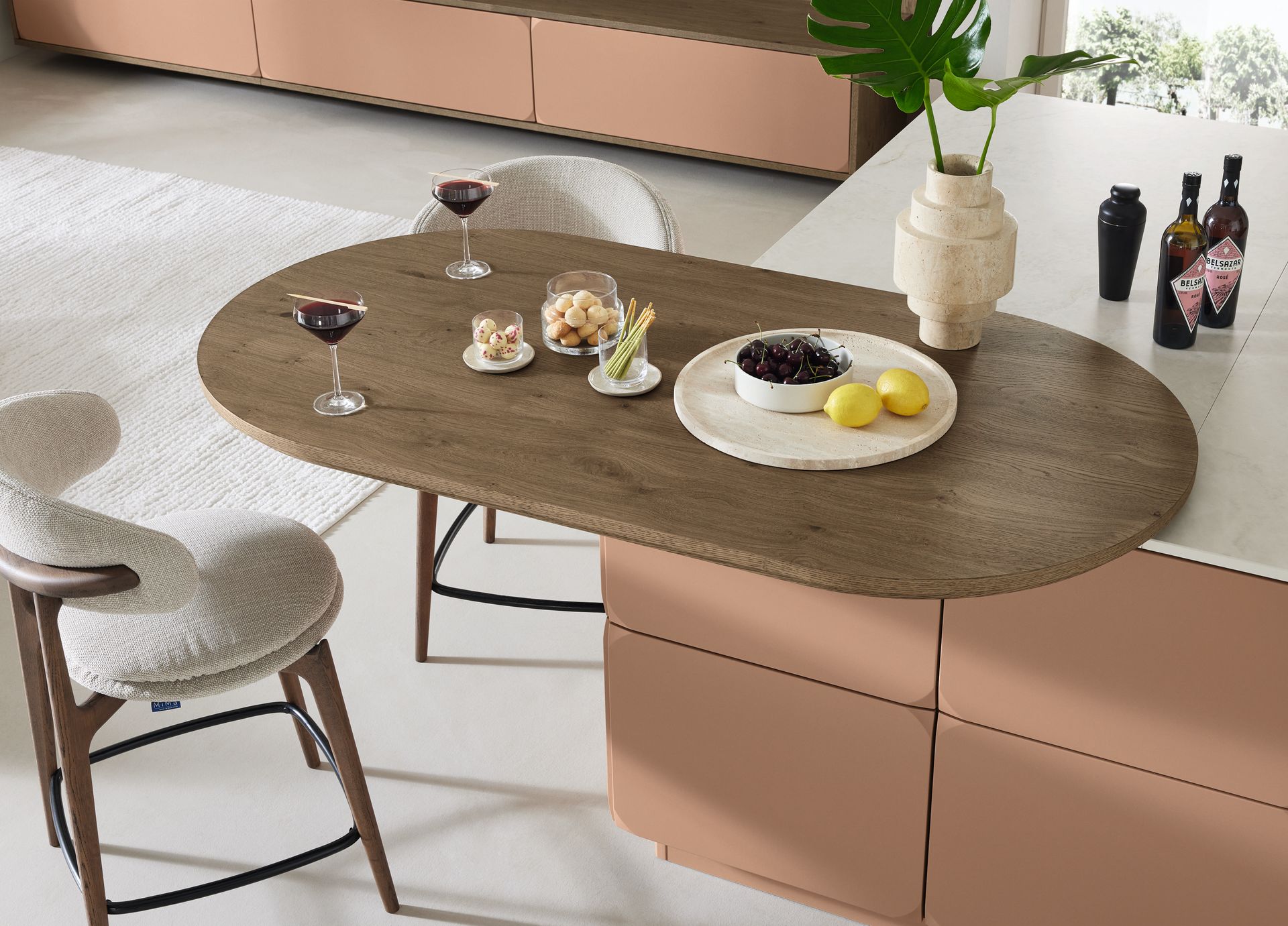 Élégante table à manger avec assiettes, verres à vin, fruits et vase, dans une cuisine moderne.