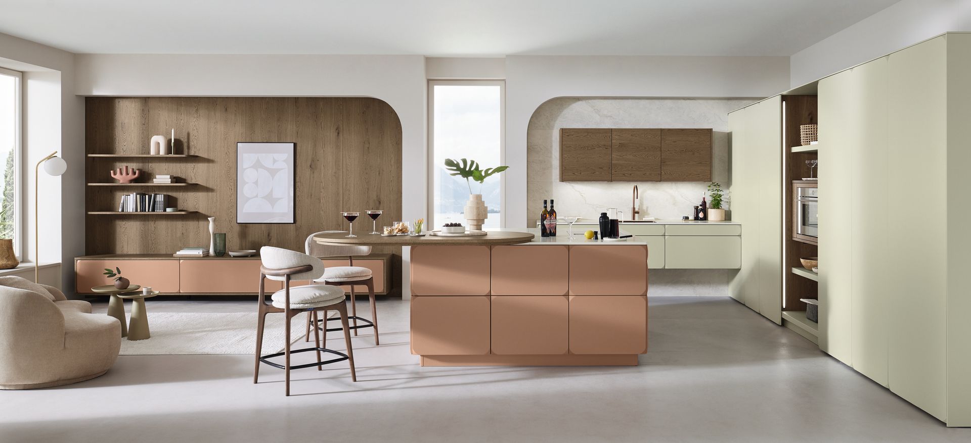 Cuisine ouverte avec îlot central couleur pêche, éléments en bois et table à manger avec tabourets.
