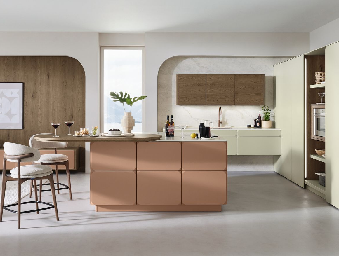 Cuisine moderne ouverte avec îlot central couleur pêche, éléments en bois et table à manger.